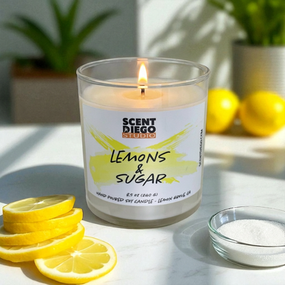 Candle labeled 'Lemons & Sugar' with lemons and sugar on a table.  The wick is lit with a flame.