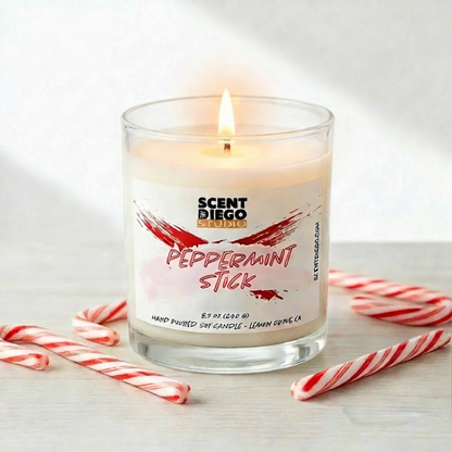 Scented candle labeled 'Peppermint Stick' with candy canes on a light background.  This candle is lit.